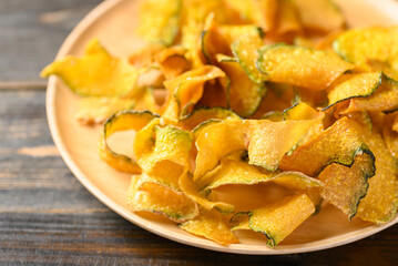 Pumpkin chips on wooden plate, Healthy vegan snack