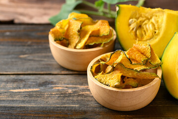 Pumpkin chips in bowl on wooden background, Healthy vegan snack