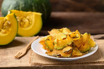 Pumpkin chips on plate with wooden background, Healthy vegan snack