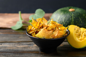 Pumpkin chips in bowl on wooden background, Healthy vegan snack