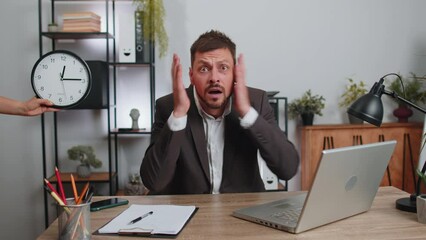Businessman programmer software developer working on laptop at office with anxiety checking time on clock, being in delay, deadline. Concentrated male freelancer business man worrying to be late