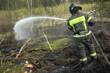Firefighter extinguishes forest. Lifeguard pours water from hose. Work of rescue service.
