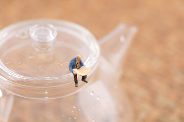 reader on a teapot in miniature