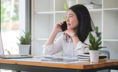 Businesswoman talking on mobile phone while sitting in office.