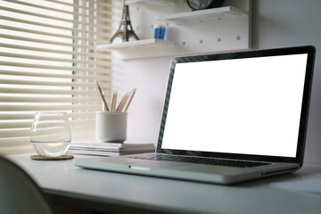 Mock up laptop computer, coffee cup and potted plant on white table. Empty screen for your advertise text..