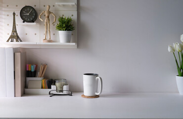 Creative workplace with supplies, house plant and coffee cup on white table. Copy space for your advertise text.