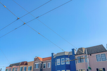Colorful row of houses in San Francisco, California with a view of electric cables at the front