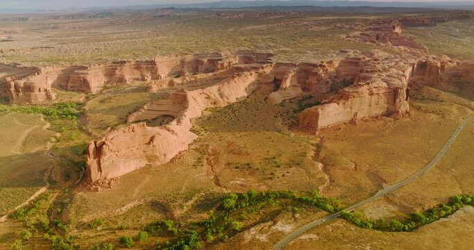 Scenic picture of wonderful canyons of Utah, USA. Drone footage over the rocks. Road crossing the area and greenery rarely growing in desert.