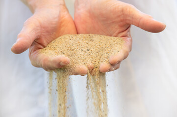 Fine sand trickles through a woman's hands. The sand symbolizes the passing of time.