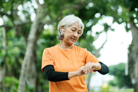 Happy athletic Senior woman checking her smartwatch in the park