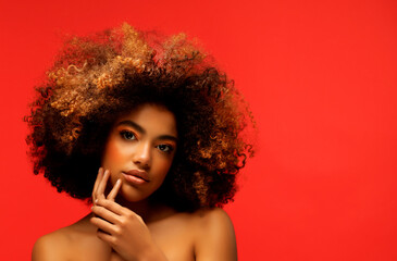 Fototapeta premium Young beautiful african american woman with afro hair. Glamour makeup. Red Background.