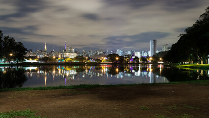 View of Ibirapuera Park, first metropolitan park in São Paulo, Brazil, and one of the most visited parks in South America at night. In the background part of the city’s skyline reflected in a lagoon