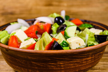 Ceramic plate with greek salad on wooden table