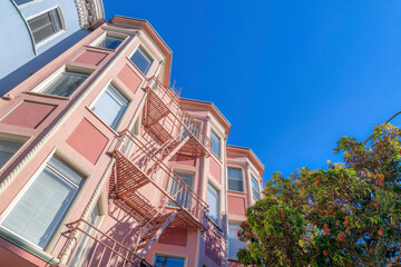 Low angle view of a pink apartment building with emergency staircase in the middle