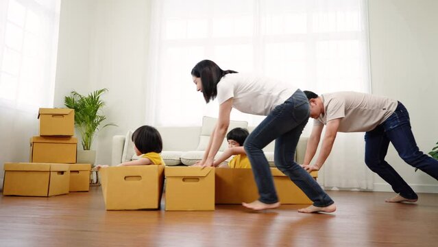 New House, a Happy Asian family with two children playing is pushing cardboard boxes together into their in-house, Moving Home, slow motion