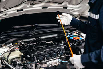 Mechanic inspecting oil level in a engine at garage workshop, Car auto services and maintenance...