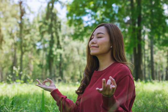 Portrait image of a young woman with closed eyes meditating in the park
