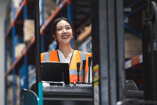 Smart engineer woman worker doing stocktaking of product management in forklift machine on shelves in warehouse. Factory physical inventory count.
