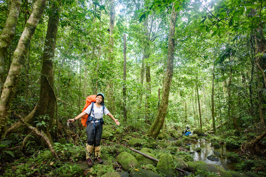 Backpackers stand happily in the vast green forest.