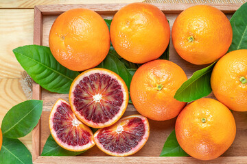 Blood oranges, or Red oranges with leaf on wooden table. 