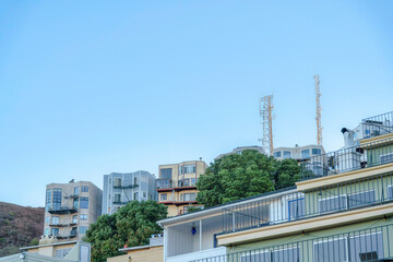 Low angle view of apartment buildings with balconies and a view of cell towers in San Francisco, CA