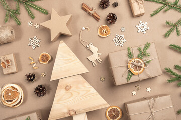 Xmas composition. Homemade wooden Christmas tree, gifts, holiday decor on craft beige background,...