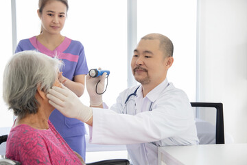 Obraz premium Asian confident doctor examine the eye of senior patient in hospital
