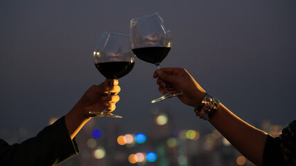 The Couple  hand with wine glasses have a romantic dinner on the rooftop with  sunset in a...