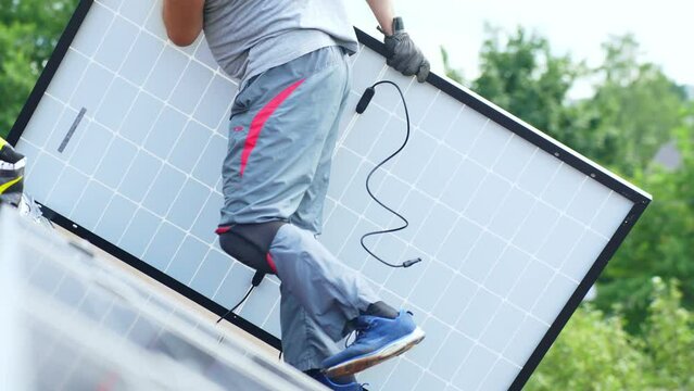 Worker moving solar panel on a roof for mounting