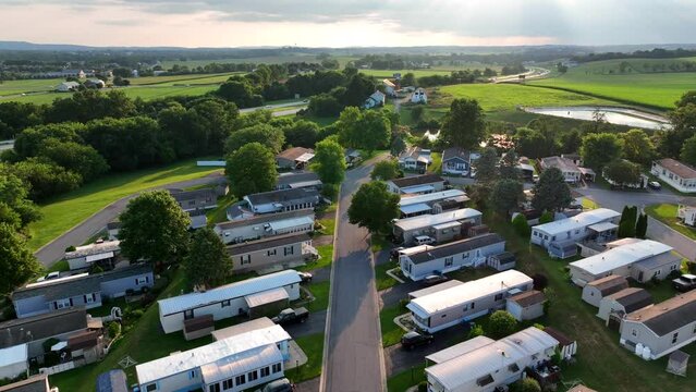 Summer evening in USA. Aerial pullback reveal of mobile home modular trailer park. Houses in rural America.