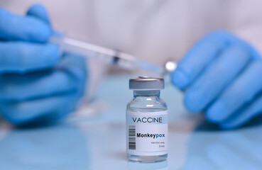 Monkeypox vaccine vial on the background of a doctor in medical gloves, a vial and a syringe. Monkeypox 2022 virus. Monkeys may harbor the virus and infect people.The concept of medicine, healthcare