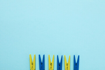 Fototapeta premium Clothespins in colors of Ukrainian flag on blue background