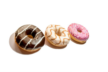 three delicious donuts with chocolate, caramel and berries on a white background, close-up, in the center of the frame