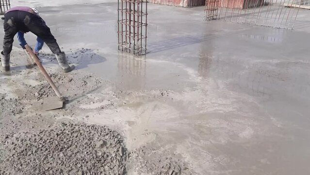 A worker Leveling PCC Foundation Concrete slab On A New Building Construction Site. Pouring concrete slab and concrete pouring during commercial concreting