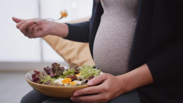 Happy Asian pregnant woman eats healthy food for her unborn baby.