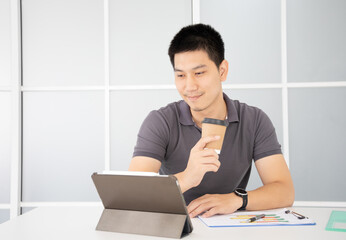 Asian businessman using tablet at home, internet marketing , freelance , working at home , online learning , work from home concept.