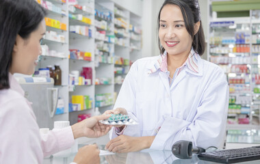 Happy female pharmacist giving prescribed medicine to customer in drug store