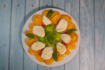 Green and Orange tomato and mozzarella salad with basil leaves and olive oil. High quality photo