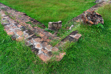 Ancient brick wall and walkway with green grass in Thailand