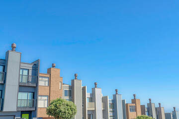 Fototapeta premium Complex townhouses in a slope with chimney flues against the clear sky in San Francisco, California