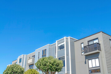Fototapeta na wymiar Townhomes with flat roof structures and gray wood siding in San Francisco, CA