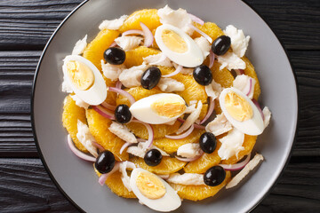 Remojon Andaluz contains fresh oranges, onion, boiled eggs, black olives and delicious salt cod close-up in a plate on the table. Horizontal top view from above