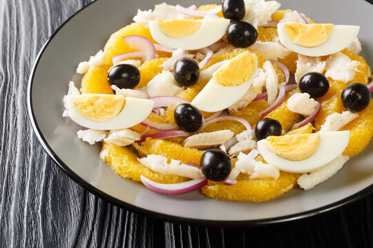 Remojon Andaluz contains fresh oranges, onion, boiled eggs, black olives and delicious salt cod close-up in a plate on the table. Horizontal