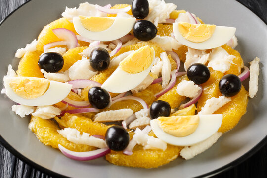 Remojon salad of oranges, boiled salted fish, eggs and red onions close-up in a plate on the table. Horizontal