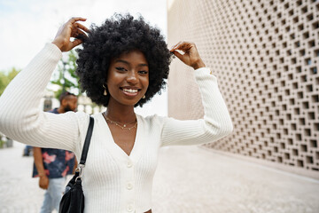 Portrait of young african woman with afro hairstyle smiling in urban background