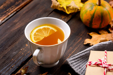 Autumn mood concept. Hot tea with lemon and leaves on wooden background