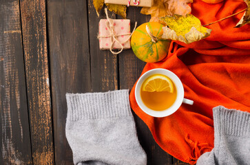 Autumn mood concept. Hot tea with lemon and leaves on wooden background