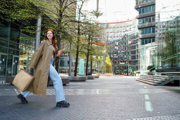 Happy fashion stylish teen girl model shopper buyer wearing trench coat holding paper shopping bags...