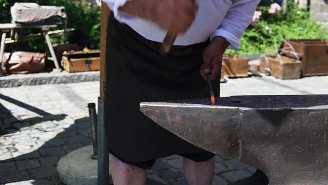At the Wallenstein Festspiele in Altdorf, Bavaria, a man is seen forging hot iron at an anvil. No face video