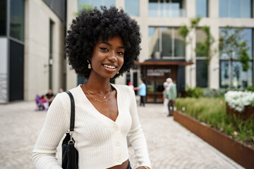 Portrait of young african woman with afro hairstyle smiling in urban background